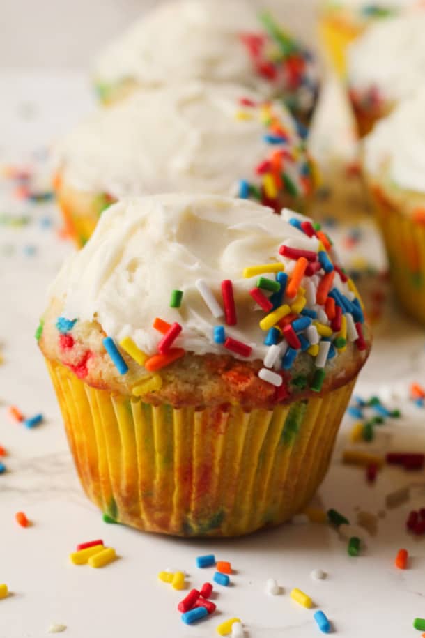 Close up view of one Gluten-free Funfetti Cupcake with frosting and sprinkles all around