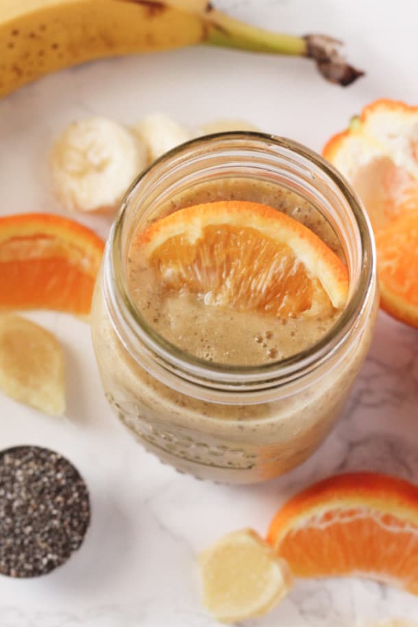Top down view of an Orange Ginger Chia Smoothie in  mason jar with a slice of orange on top