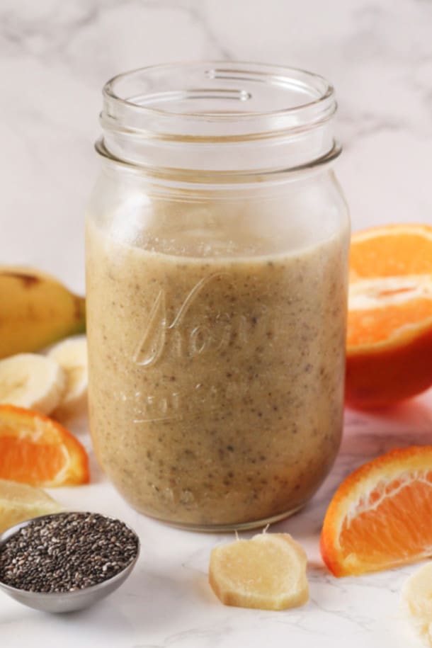 Orange Ginger Chia Smoothie in a mason jar with orange slices, ginger and chia seeds around it