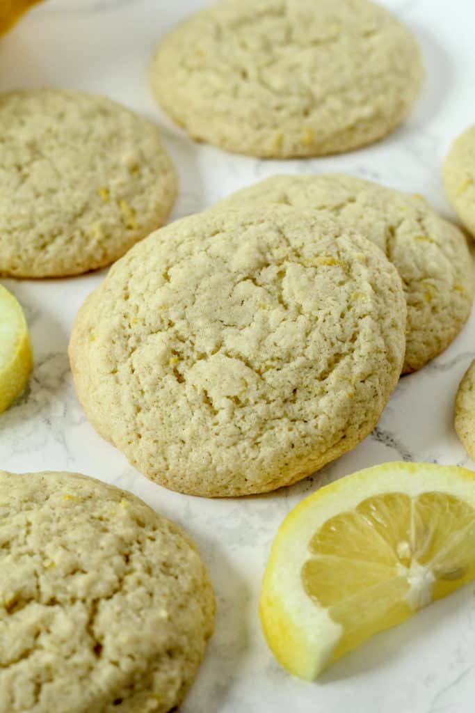 Lemon Cookies scattered around parchment paper with lemon slices