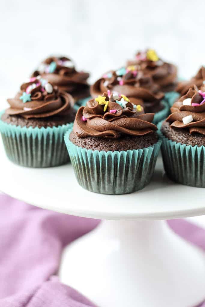 Gluten-free Chocolate Cupcakes on a cake stand with frosting and sprinkles