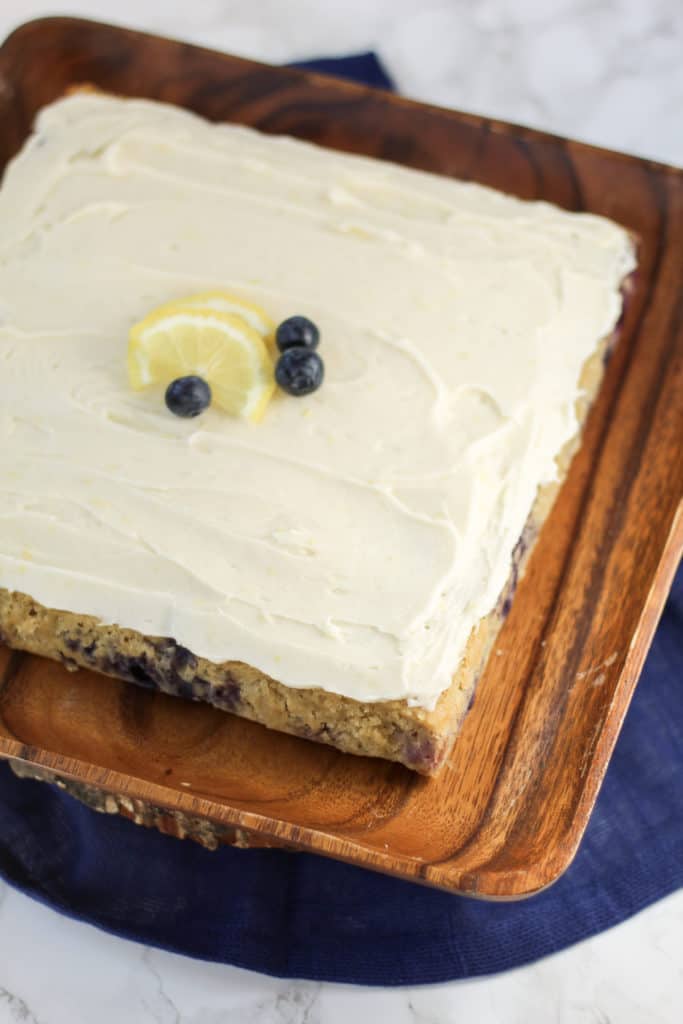 Lemon Blueberry Oat Cake on a wood tray with a slice of lemon and blueberries on top