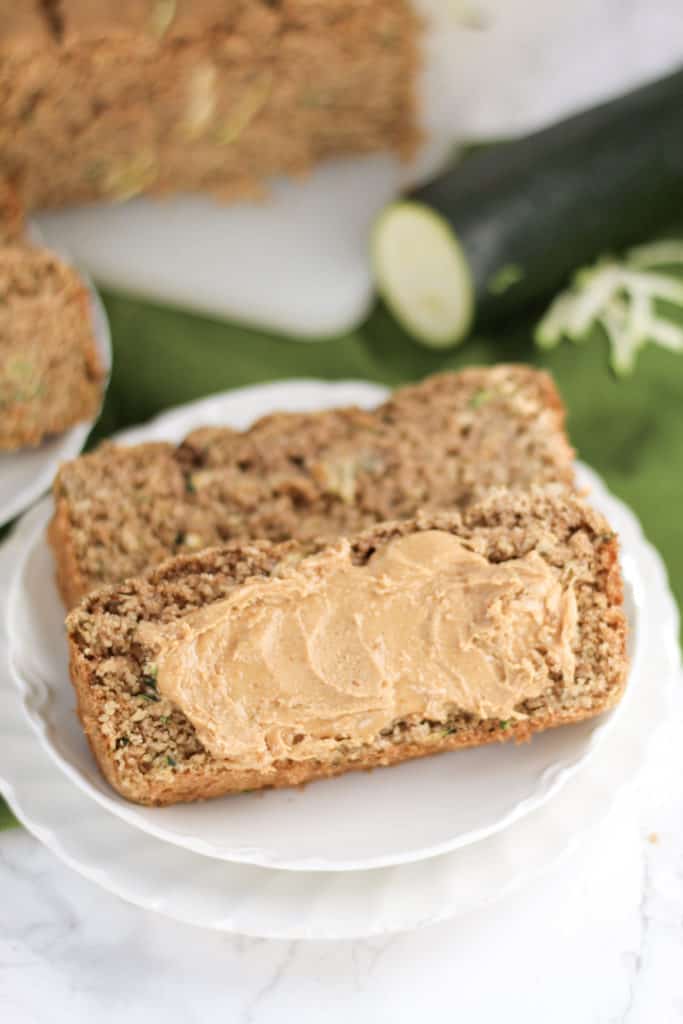 two plates stacked with two pieces of Zucchini Oat Bread with nut butter spread across the top one