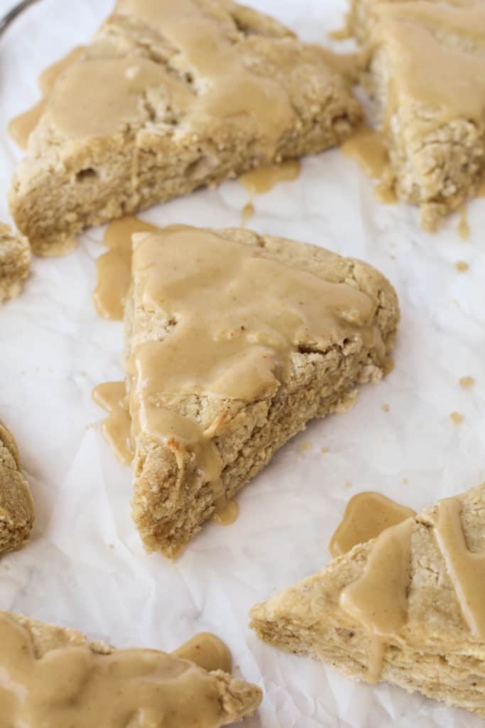 Peanut Butter Scones scattered on parchment paper with glaze on top