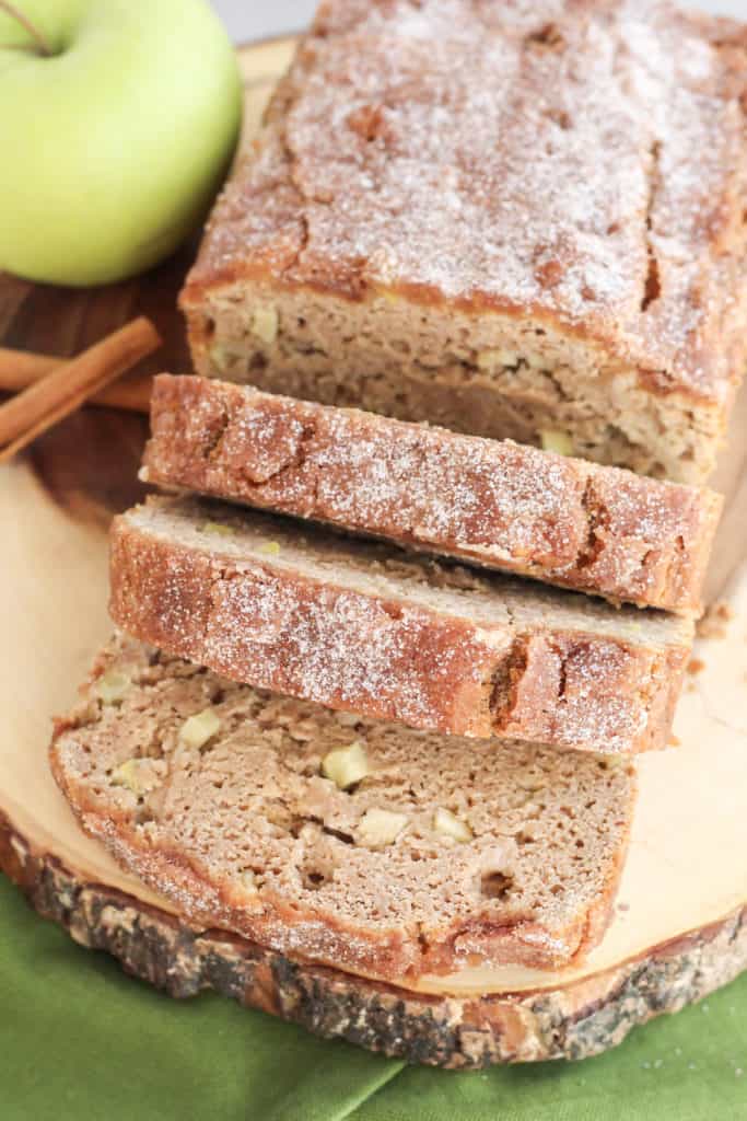 Apple Cinnamon Bread with three pieces sliced out of it, on a wood tray