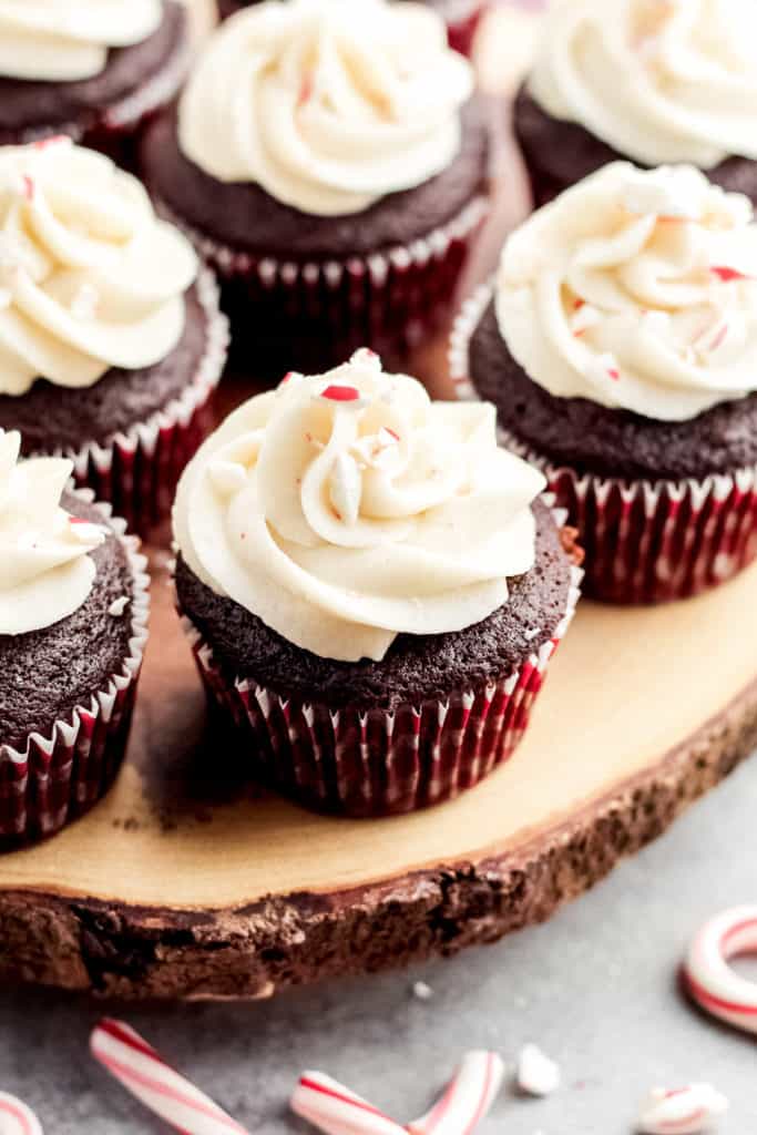 Chocolate Peppermint Cupcakes on a slice of wood, with one cupcake up close