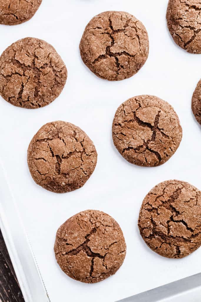 a baking tray with parchment paper and molasses cookies on top