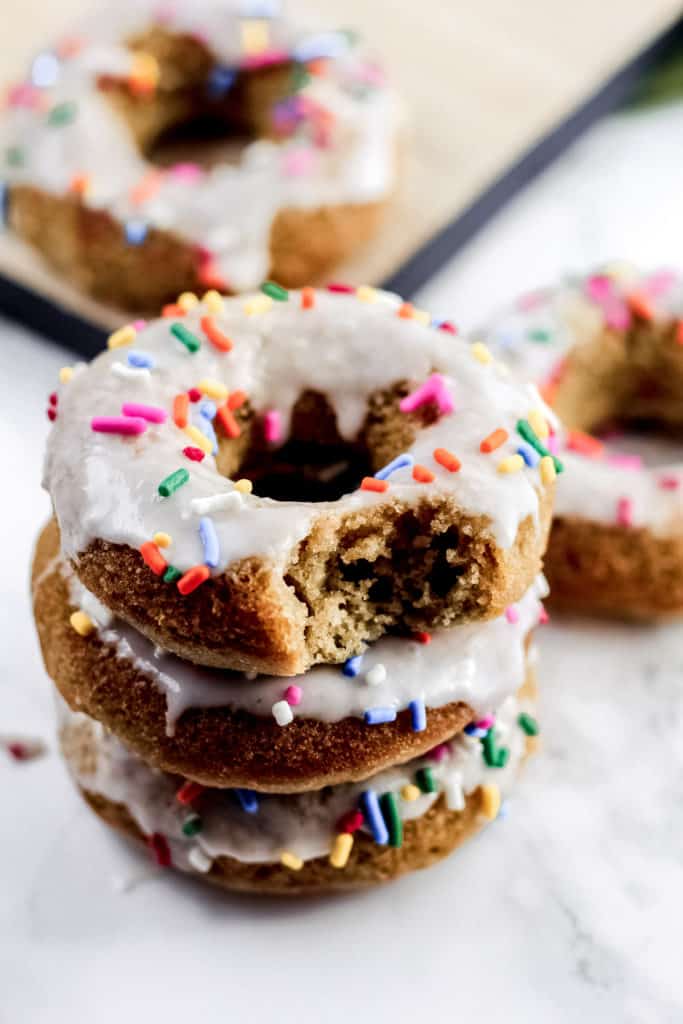 a stack of three Healthy Vanilla Donuts with a bite taken out of the top donut