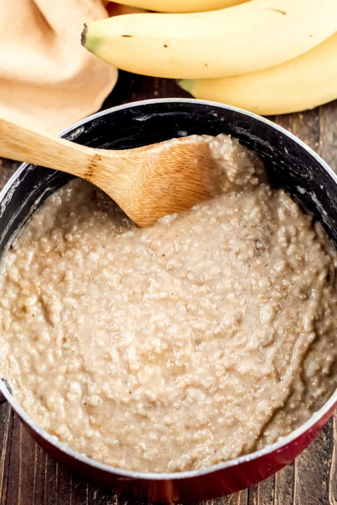 pot filled with Banana Steel Cut Oats with a wood spoon inside