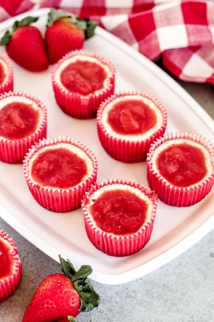 a tray of Skinny Mini Strawberry Cheesecakes with strawberries around