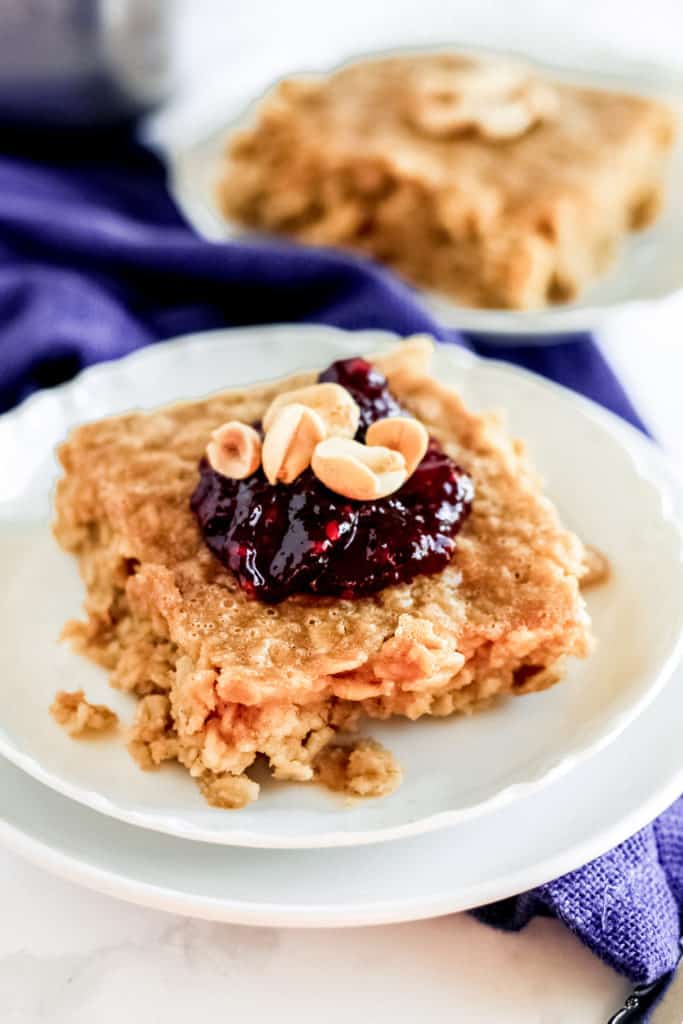 plate of a piece of peanut butter oatmeal topped with jelly and peanuts