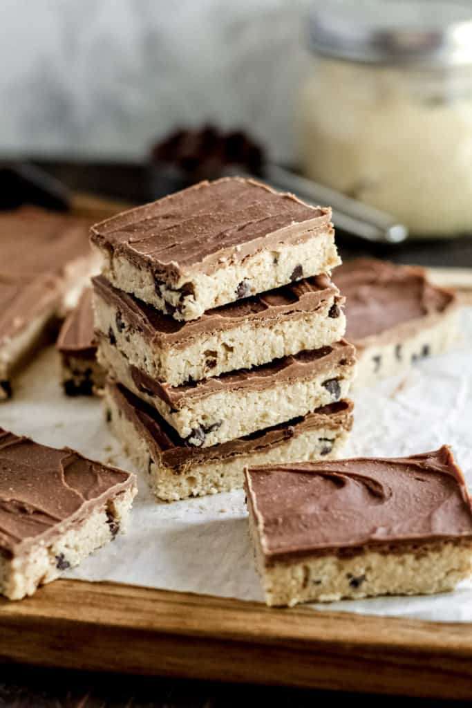 A stack of four no bake cookie dough bars surrounded by other bars