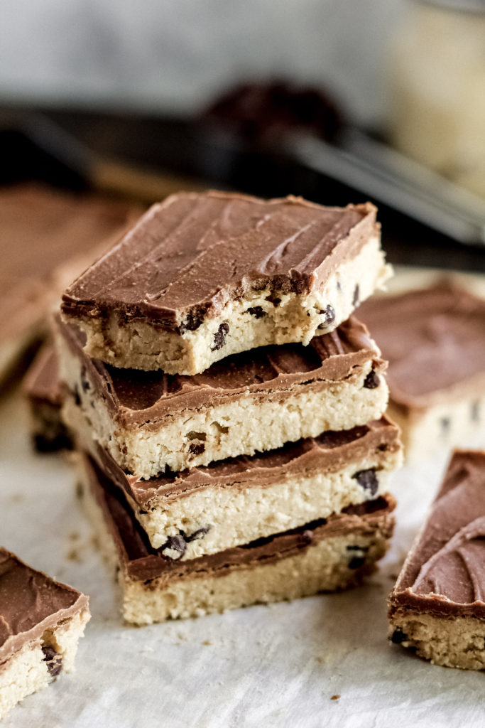 A stack of four no bake cookie dough bars with a bite taken out of the top bar