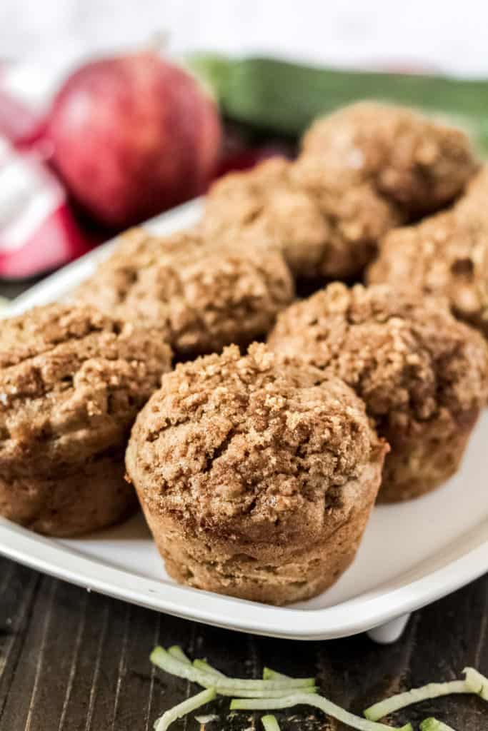 Close up view of one apple cinnamon zucchini muffin on a white tray