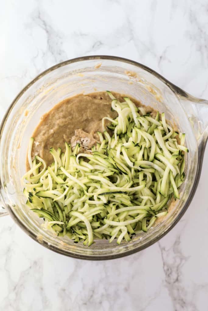 Muffin batter and zucchini in a bowl