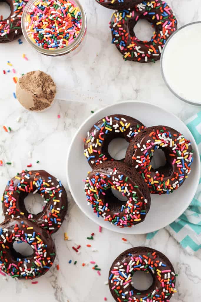 Chocolate donuts with sprinkles on a plate and on the counter