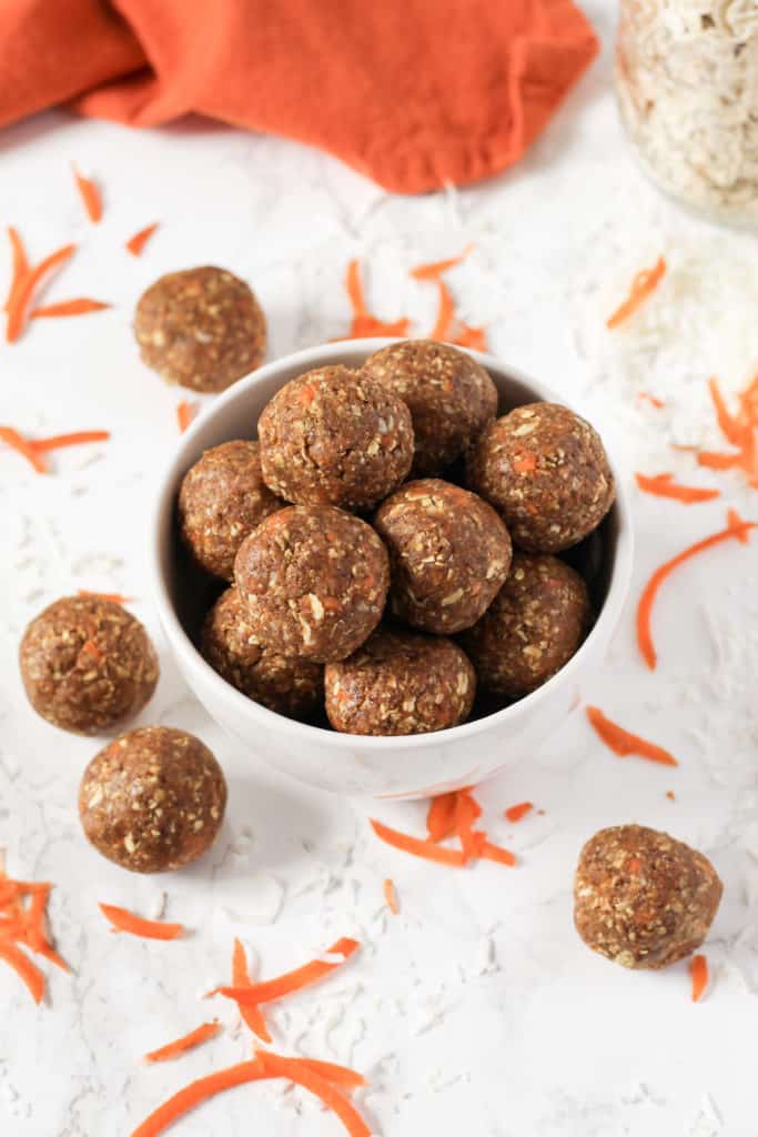 Bowl of snack balls with shredded carrot around.