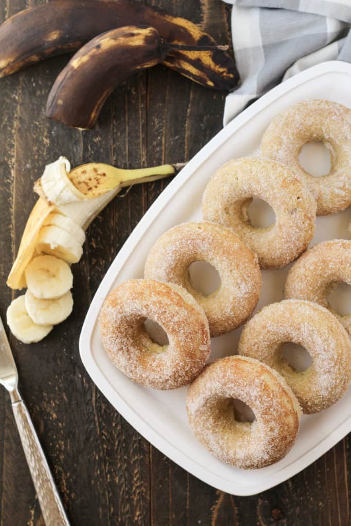 Tray full of donuts with bananas on the side.