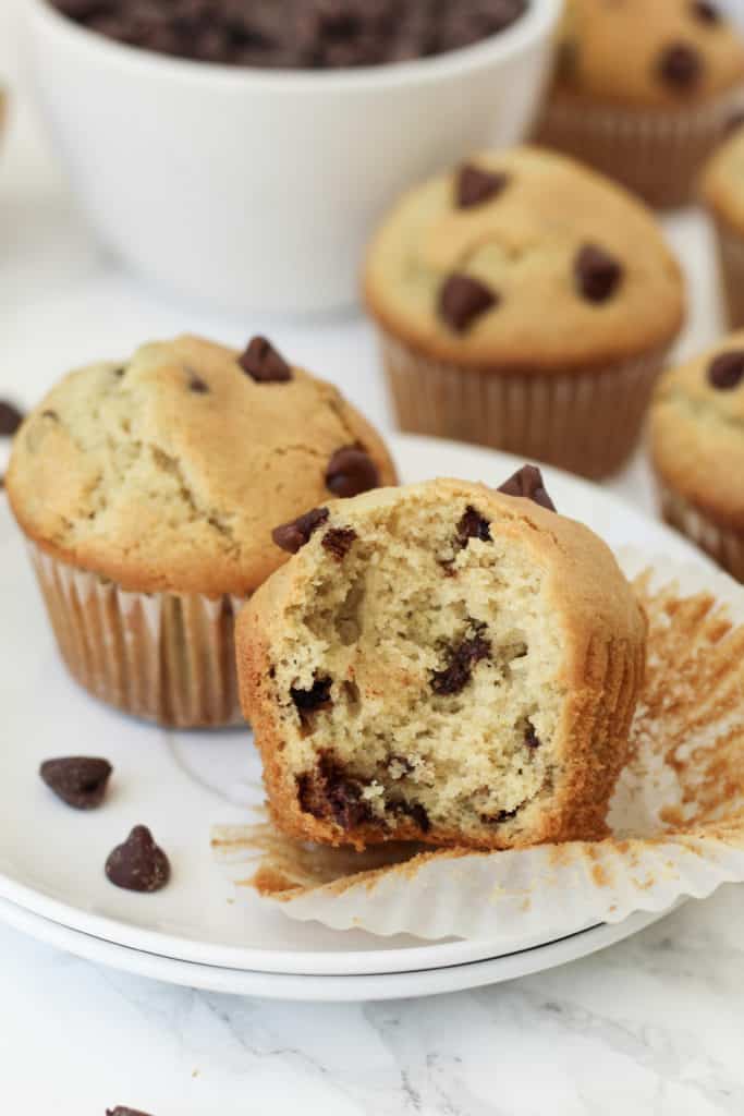 A muffin on a plate with a bite taken out of it.