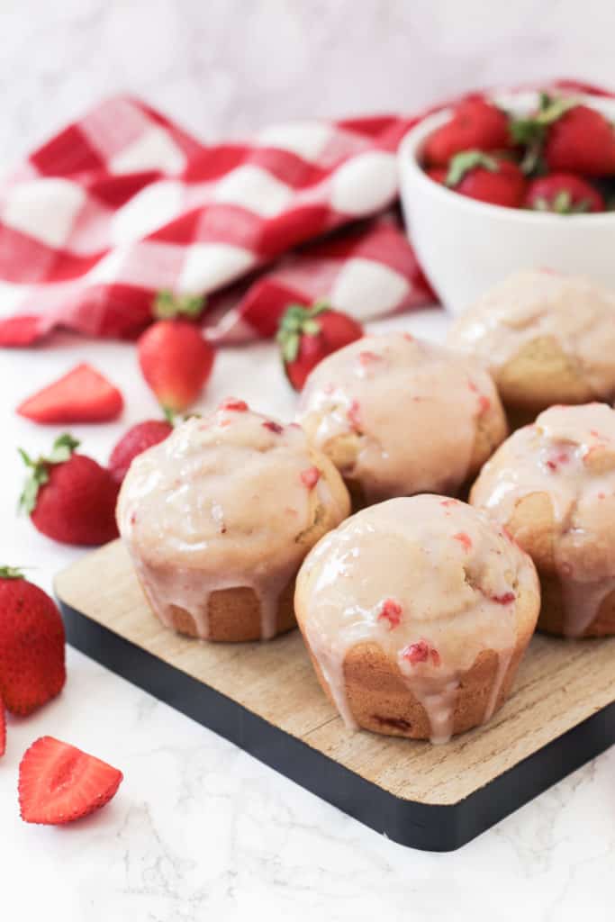 Tray of strawberry muffins with strawberries around.