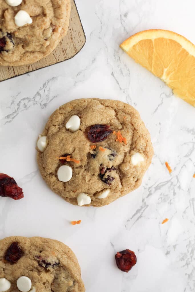 Close up of one cookie with orange zest, cranberries and white chocolate chips.