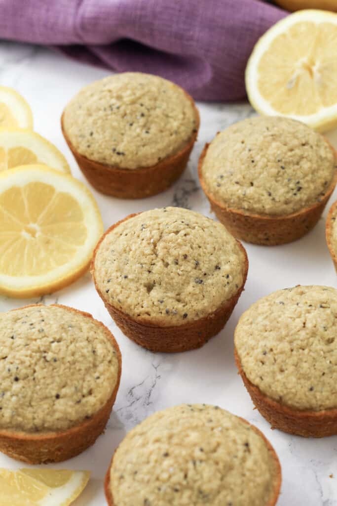 Muffins on a counter with lemon slices next to it.