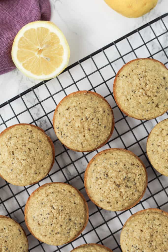 Muffins on a cooling rack with a lemon behind.